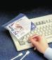 Preview: In the image, you see a hand holding a slightly transparent bag labeled "PC Buds". Next to it, there's a white keyboard and two cotton swabs on a blue background.