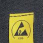 Preview: The image displays a yellow label with a black symbol in the shape of a triangle and a hand. Below it reads "ESD". The background is made of dark denim texture.