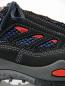Preview: Das Bild zeigt einen Sport- oder Wanderschuh in Schwarz mit blauen und roten Akzenten. Der Schuh hat Netzmaterial für Belüftung und eine robuste, graue Sohle mit stabilisierenden Elementen.