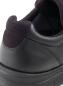 Preview: The image shows the back of a black sneaker. The shoe is made of a smooth leather surface and has a padded, dark blue collar.