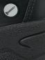 Preview: Das Bild zeigt einen Teil eines schwarzen Schuhs aus strukturiertem Material. Auf der Oberfläche ist ein kleines rundes Symbol mit einem Bleistift abgebildet.