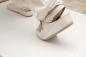 Preview: The image shows a foot in white shoes on a smooth, light floor. The shoe has an adjustable strap. The background is blurry, and the focus is on the shoe.