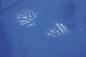 Preview: On a smooth blue surface, two footprints are visible, left with a white material. The prints show the shape of shoes.