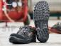 Preview: The image shows a pair of safety shoes with a sturdy, textured sole. The shoes are black with orange accents and a practical closure system.