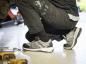 Preview: A person is sitting on the floor, wearing black work pants and gray athletic shoes. Tools are scattered on the floor, and the surroundings resemble a workshop.