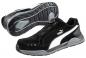 Preview: The image shows a black sports shoe with gray and white accents. It features a flat sole with good tread and a unique lacing mechanism instead of traditional laces.