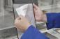 Preview: In the picture, there are hands holding a document titled "ASSEMBLY". The hands are in blue gloves, and the background appears to be a work environment.