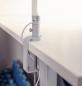 Preview: The image displays a white desk lamp attached to the edge of a table. It features a cylindrical shaft and a clamp for stabilization. The background appears bright and neutral.