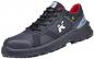 Preview: Der Schuh ist ein sportlicher, schwarzer Sneaker mit roten Akzenten. Er hat ein gepolstertes Innenfutter, eine stabile Sohle und eine verstärkte Zehenkappe für zusätzlichen Schutz.