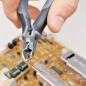 Preview: A hand is holding pliers that are cutting thin copper wire. In the background, there is a circuit board with various electronic components and a golden surface.