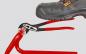 Preview: A black safety shoe is standing on a red pair of pliers. The pliers have a black, shiny head and red handles that are pressed together while the shoe is on top.