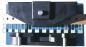 Preview: The image shows a device with a black top part and a blue base. Below, two round rollers are visible. On the side, there are several green and white switches or buttons.