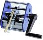 Preview: The image shows a manual machine with a large, rectangular casing and a crank. At the front, a flexible band runs through the machine, which has rotating mechanisms in the center.