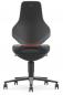 Preview: The chair features an ergonomic, high backrest in an elegant, matte black. The seat is round and has a slight curve. Beneath the seat, five caster feet extend. An orange accent line is visible.