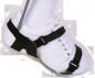 Preview: The image shows a white sports shoe that is secured with a black holder or strap. The shoe is positioned on a foot, and a gray sock is visible.