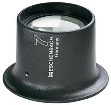 The image shows a black magnifying glass with highly curved glass. The base is round and has a matte finish. On the side, it reads "Eschenbach Germany" and the number "7".