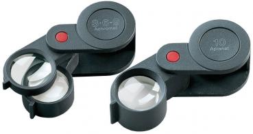 The image shows a handy magnifying glass with an adjustable, round glass area. It has a black plastic frame and a red button. The magnification is 10x.
