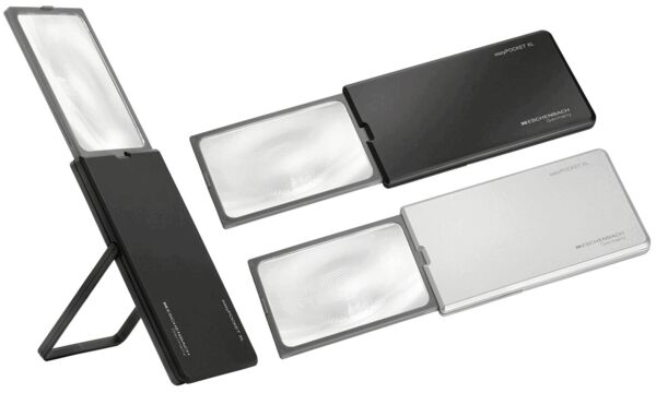 The image shows a black, folding magnifying glass with a large, clear lens on the left side. The design is compact and ideal for travel.