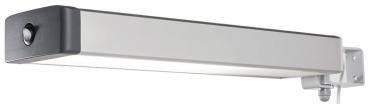 The image displays an elongated wall lamp with a silver casing and black ends. It is simple and minimalist, featuring a light-emitting surface in the center. There is a mounting bracket on the back for wall attachment.