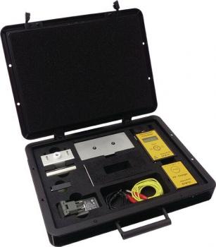 The image shows an open, black suitcase with various tools and devices. Inside, there are two yellow devices, a metal part, and cables, all neatly arranged.