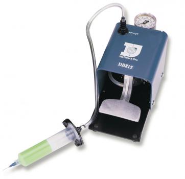 Das Bild zeigt ein medizinisches Gerät: eine kompakte, graue Pumpe mit einem Manometer und einem transparenten Schlauch, der zu einer Spritze führt. Die Spritze hat einen grünen Kolben.