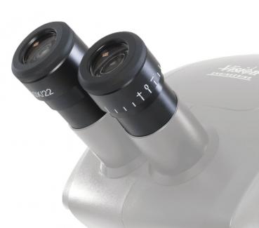 The image shows a microscope attachment with two round eyepieces. The eyepieces are black with numbers and a possible magnification factor. The body is silver-colored.