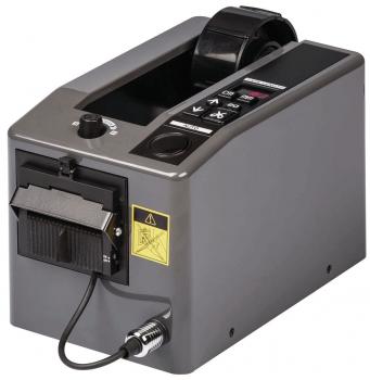 The image shows a gray device with a smooth surface and a slot on the top. On the front, there are buttons and a compartment for dispensing labels or tickets.