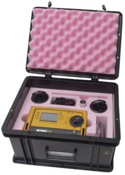 The image shows an open, black suitcase with a foam-padded interior. Inside, there is a yellow device with a display, buttons, and additional accessories.