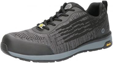 The shoe is sporty and modern, primarily in black with gray and metallic accents. It features a textured-looking surface, laces, and a sturdy, rubberized sole.