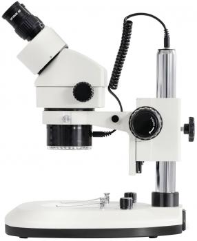The image shows a microscope with a vertical, stable base. At the top, there is an eyepiece, and below it, a circular lens. Numerous knobs and cables are visible.