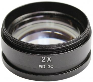 The image shows a black lens with a two-fold magnification. The lens has a round edge and is transparent in the middle. On the side it reads "2X WD 30".