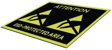 The image shows a rectangular mat with a black background. In the center, it reads "ATTENTION" and "ESD-PROTECTED AREA" in yellow font. There are two warning symbols in the form of stylized triangles.