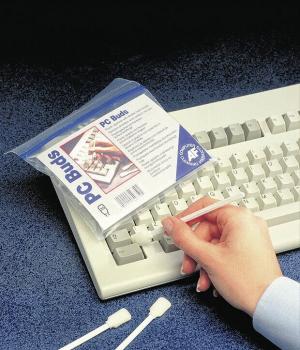 In the image, you see a hand holding a slightly transparent bag labeled "PC Buds". Next to it, there's a white keyboard and two cotton swabs on a blue background.