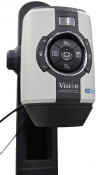 The image shows a device for optical magnification. It has a round, central button with several control knobs around it and is mounted on a stable, black stand.