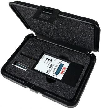 The image shows a closed, black case with a matte black interior surface. Inside, there is a device with an LCD display and several buttons, as well as a small pen.