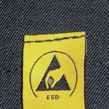 The image displays a yellow label with a black symbol in the shape of a triangle and a hand. Below it reads "ESD". The background is made of dark denim texture.