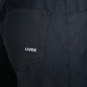 Das Bild zeigt den unteren Teil eines schwarzen Kleidungsstücks, vermutlich eine Hose oder Latzhose. Am linken Hosenbeinteil befindet sich eine aufgesetzte Tasche mit dem weißen Schriftzug ?Uvex?.