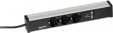 The image shows a black power strip with three Schuko sockets and two USB ports for power supply. It has a silver top and a cable to connect to the power source.