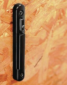 The image displays a narrow, black bar mounted on a wooden surface. The surface is rough and exhibits a wood grain with visible fiber patterns.