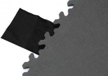 The image displays a matte, green surface with a jagged edge, next to which lies a piece of black fabric. The mat has a textured surface that appears to be slip-resistant.