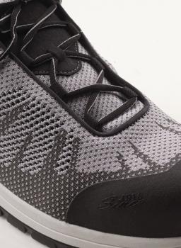 The image shows a sporty shoe in gray and black with breathable mesh material. The laces are black, and the sole is slightly raised.