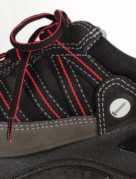 The image shows a black shoe with red and gray accents. The surface is made of fabric with a mesh design, and the laces are loosely tied. The shoe has a sturdy sole.