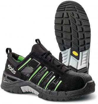 The image shows a black safety shoe with green accents. It has a sturdy rubber sole with a textured profile and reinforced toes for added protection.