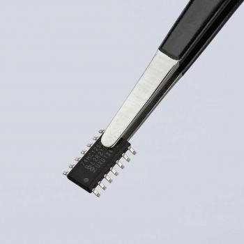 In the image, a small, rectangular chip is visible, held by tweezers. The chip has several metallic contacts on the sides and is black. The background is light.