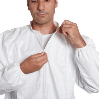 A man is wearing a white jumpsuit with a zipper. He is slightly leaning forward and pulling the zipper up with both hands.