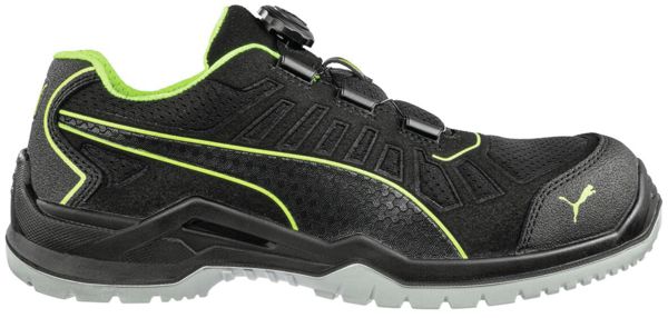 The shoe is a sporty, black sneaker with a green accent. It features a lace-up front and a sturdy, non-slip sole for good grip. Ideal for leisure and activities.