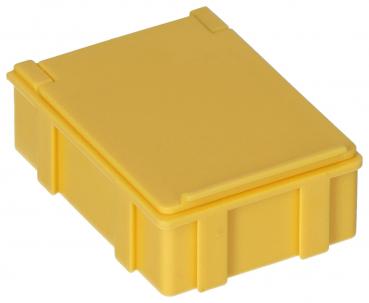 Das Bild zeigt eine kleine, gelbe Kunststoffbox mit einem flachen, abnehmbaren Deckel. Die Box hat an den Seiten vier horizontale Rillen und ist quadratisch geformt.
