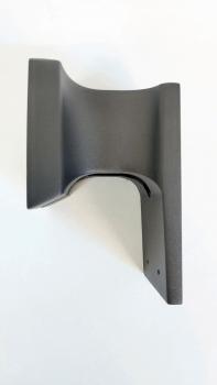 Das Bild zeigt eine schwarze Halterung mit geschwungenen Kanten. Die Rückseite ist flach und hat zwei Löcher zum Befestigen. Sie wirkt stabil und hat eine matte Oberfläche.