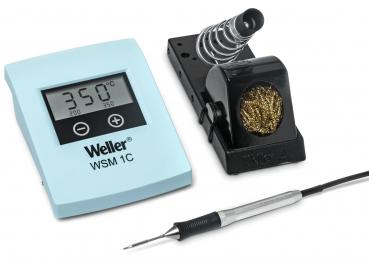 The image displays a soldering iron kit. It includes a digital thermometer with temperature display, a soldering iron with a rounded tip, and a holder with a cleaning wire.