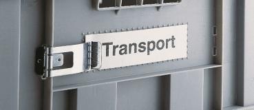 The image shows a gray transport box with a metallic clasp. On a plate, the word 